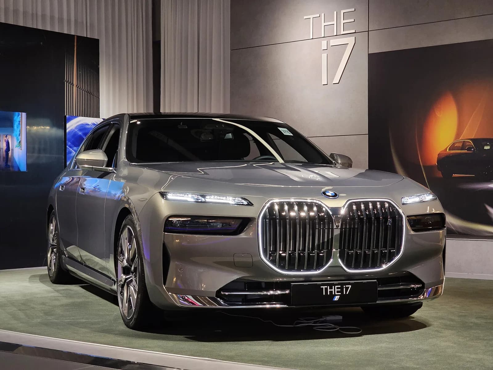 Oxide Grey BMW i7 xDrive60 (7 Series G70) sedan in a showroom, front three-quarter view